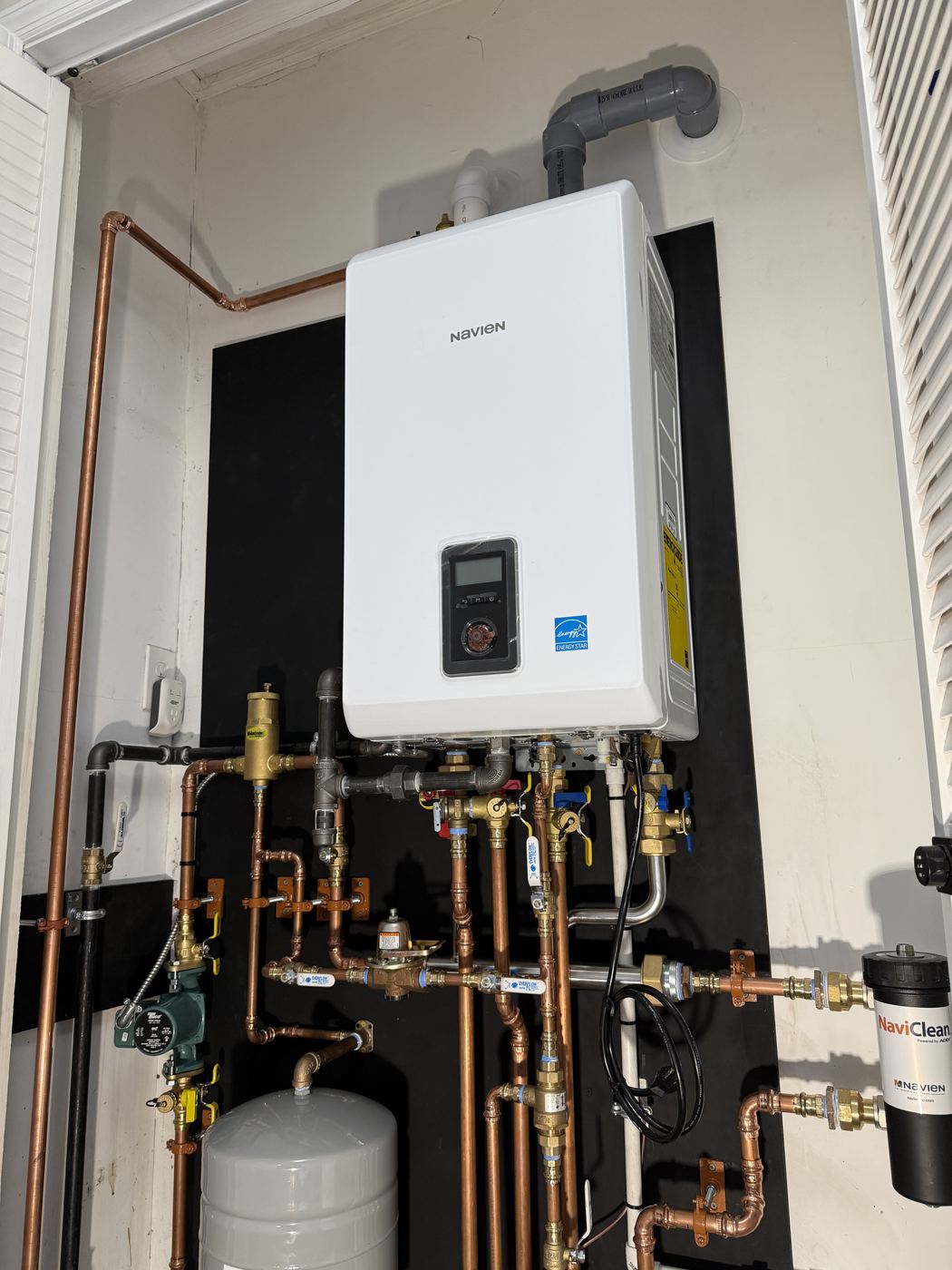 Navien combi boiler in a utility closet with copper piping, providing heat and hot water for the house